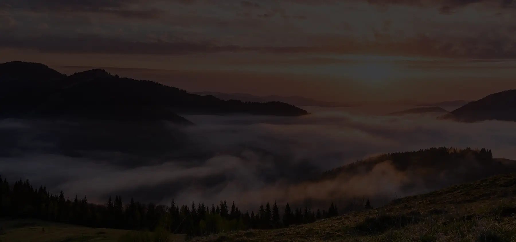 A person standing on a mountain peak at sunrise — representing success